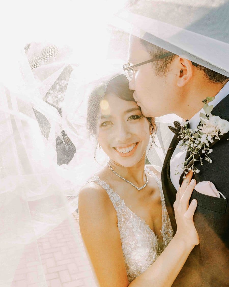 Bride and groom beneath a veil at golden hour — documentary wedding photographer