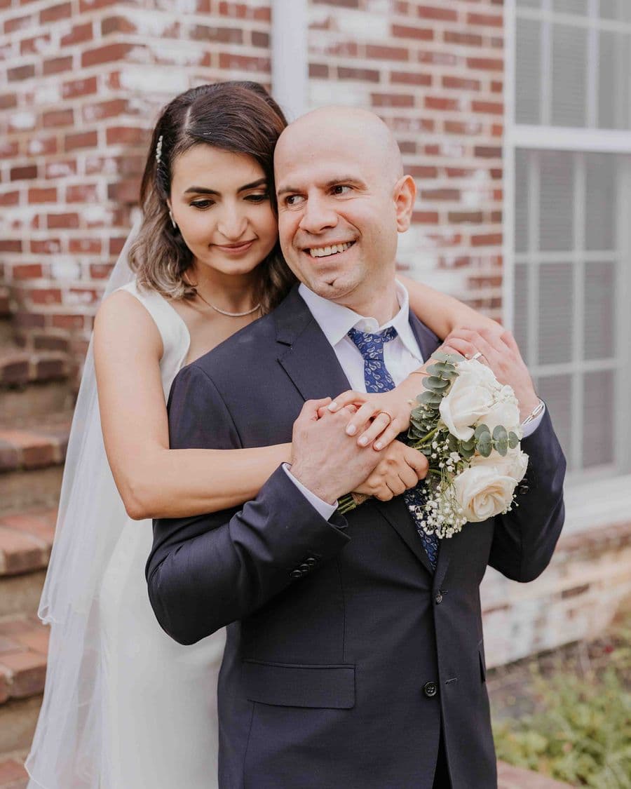 Bride and groom embracing against a brick wall — documentary wedding photographer